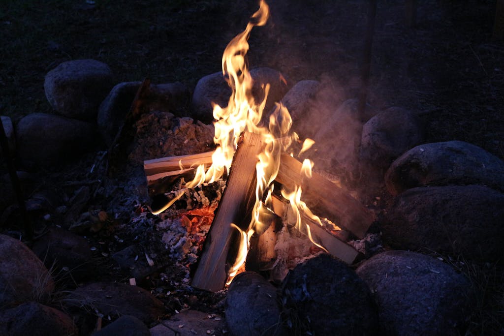 A warm, glowing campfire surrounded by rocks, creating a peaceful outdoor scene.