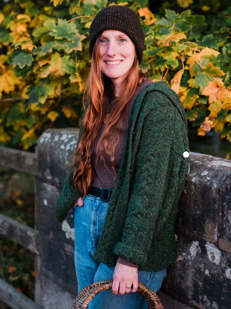 Bex Northman, forager and founder of Wild & Weeds, smiling by a woodland bridge in autumn