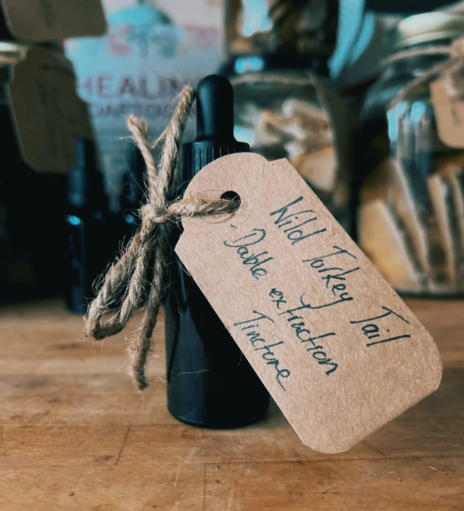 A small dark dropper bottle tied with a handwritten brown tag, made at a herbal remedy workshop